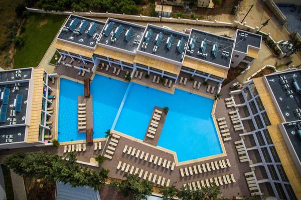 Luftaufnahme des Gouves Water Park Holiday Resort mit zwei Schwimmbecken und vielen Liegen.