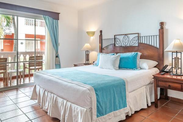 Schlafzimmer im Marien Puerto Plata Hotel mit einem Bett, Kissen, Tischlampen und einem Telefon auf einem Nachttisch.