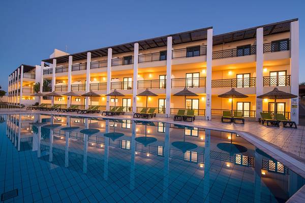 Abendliche Ansicht des Gouves Water Park Holiday Resort mit Swimmingpool und grünen Liegestühlen.