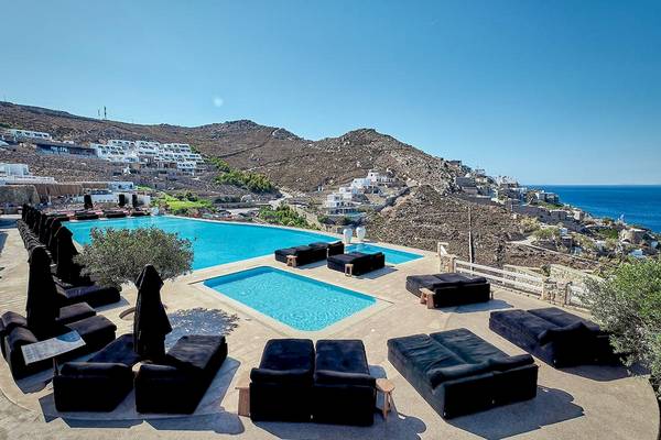 Luftaufnahme des Myconian Villa Collection Hotels mit Pool und Berglandschaft im Hintergrund.