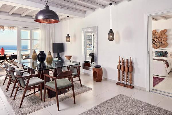 Innenansicht des Speisesaals im Myconian Villa Collection mit Glastisch, modernen Stühlen und Blick auf das Meer.