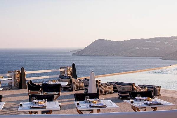 Terrasse des Myconian Villa Collection mit Blick auf das Meer und eine Insel im Hintergrund.