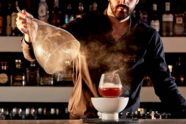 Barkeeper in einem Cocktail-Bar bei der Zubereitung eines Getränks mit einem Glas.