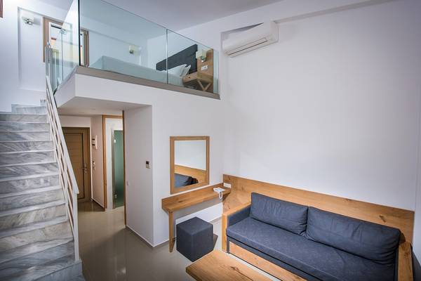 Innenbereich des Gouves Water Park Holiday Resort mit gefliester Treppe, Glasbalkon und einem Bett im oberen Stockwerk.