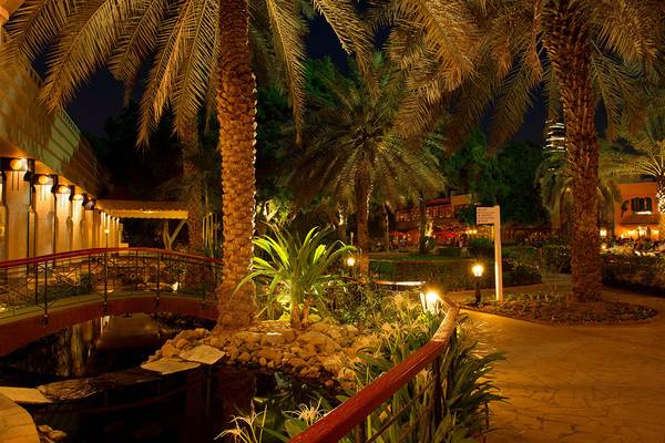 Gartenansicht des Le Meridien Abu Dhabi bei Nacht mit Beleuchtung und Palmen.