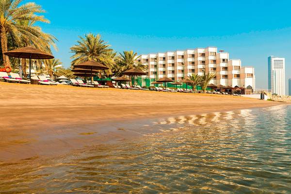 Le Meridien Abu Dhabi Hotel am Strand mit Liegen und Palmen