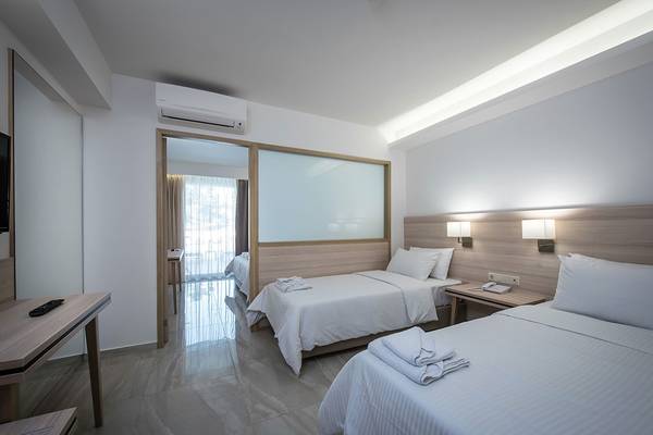 Doppelzimmer im Gouves Water Park Holiday Resort mit zwei Betten, Klimaanlage und Badezimmerspiegel.