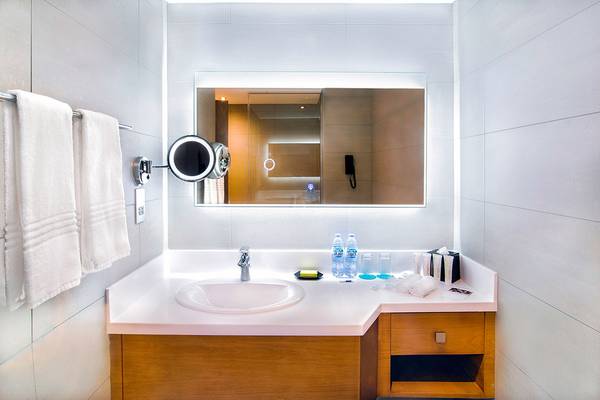 Badezimmer im Le Meridien Abu Dhabi mit Spiegel, Waschbecken und Toilettenartikeln.