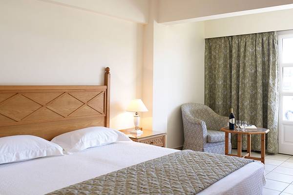 Schlafzimmer im Mitsis Petit Palais Beach Hotel mit Bett, Lampe und Fenster