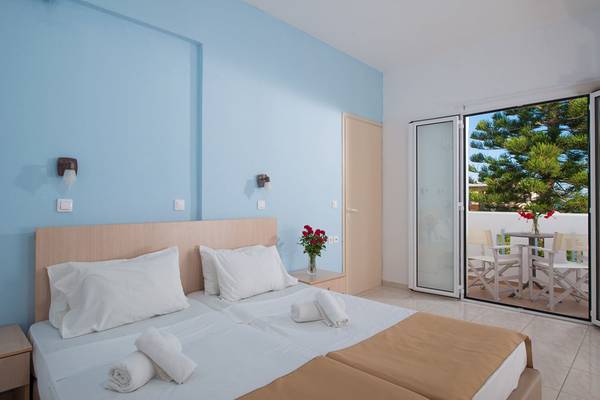 Doppelzimmer im Gouves Water Park Holiday Resort mit Blick auf eine Terrasse mit Möbeln und einer roten Blume in einem Glas.