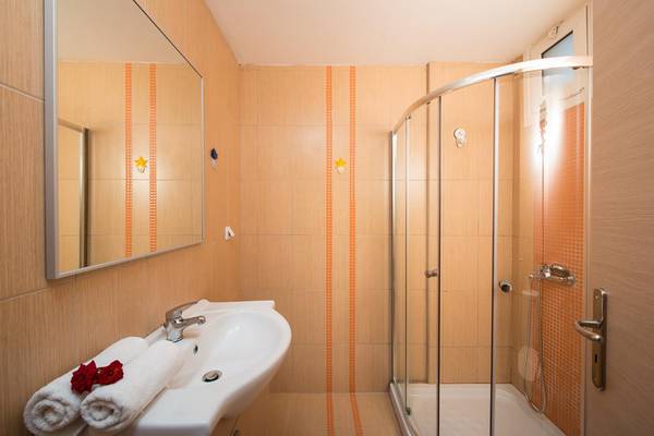Badezimmer im Gouves Water Park Holiday Resort mit einer Dusche, einem Waschbecken und Handtüchern.