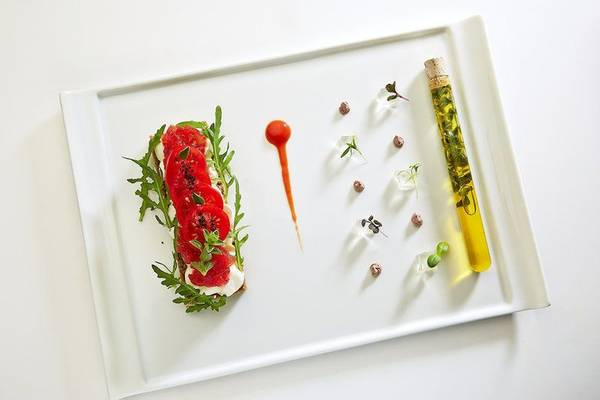 Gerichteter Teller mit Tomaten, Rucola und Öl auf weißem Hintergrund
