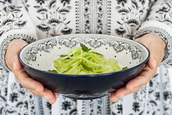 Hand hält Schüssel mit gewürztem Gurkensalat