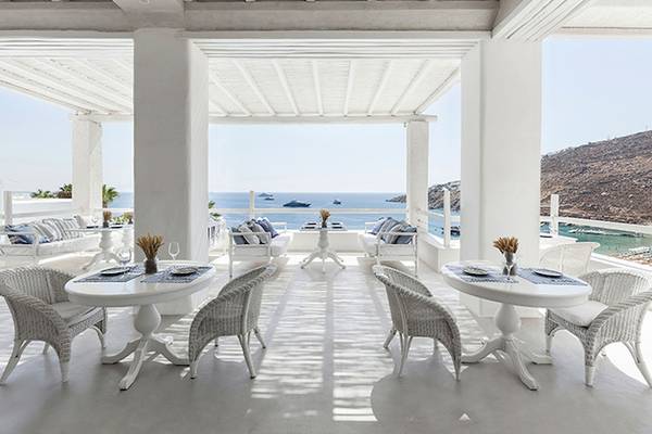 Grecotel Mykonos Blu Hotel Terrasse mit Meerblick, weiße Möbel und Tische.