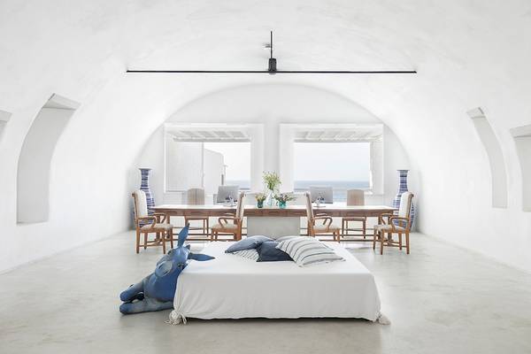 Innenraum des Grecotel Mykonos Blu mit einem Bett und einem Esstisch.
