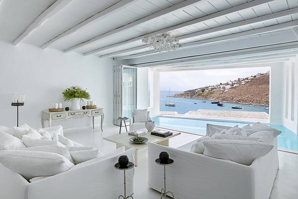 Wohnzimmer im Grecotel Mykonos Blu mit Blick auf das Meer und Inseln im Hintergrund.