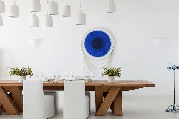 Speisesaal im Grecotel Mykonos Blu mit weißem Tisch und Stühlen, blauer Wandkunst und weißen Hängelampen.