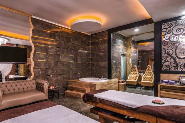 Spa-Behandlungsraum im Adalya Elite Lara Hotel mit Badewanne, Couch und Fernseher.