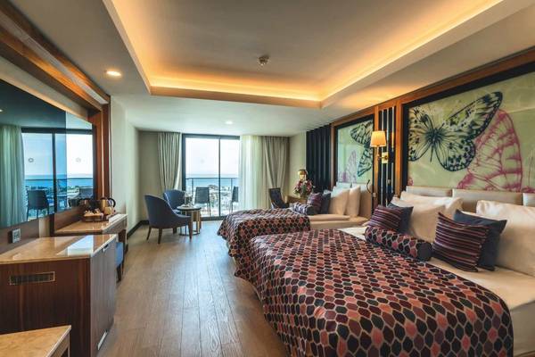 Innenansicht eines Schlafzimmers im Adalya Elite Lara Hotel mit zwei Betten, Aussicht auf das Meer und moderne Inneneinrichtung.