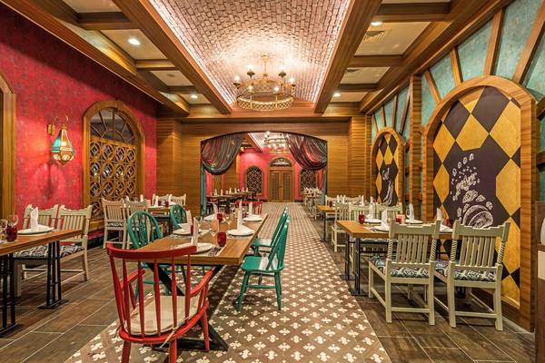 Innenansicht des Restaurants im Hotel Adalya Elite Lara mit roten Wänden, Holzdecken und farbigen Stühlen.