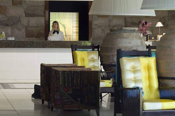 Empfangsbereich im Marmara Bodrum Hotel mit Rezeptionistin am Telefon und dekorativ eingerichteten Möbeln.