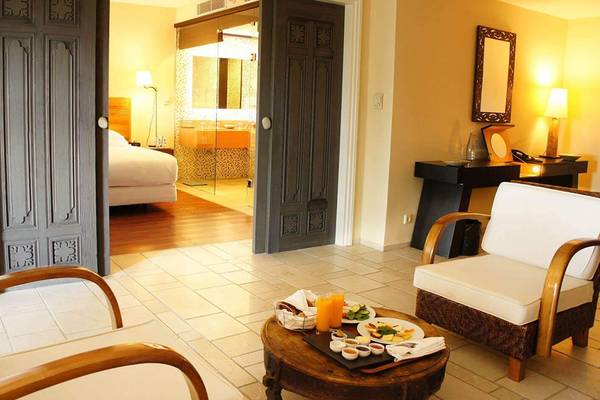 Wohnzimmer im Marmara Bodrum Hotel mit zwei Sesseln, Tisch und Frühstücksplatte.