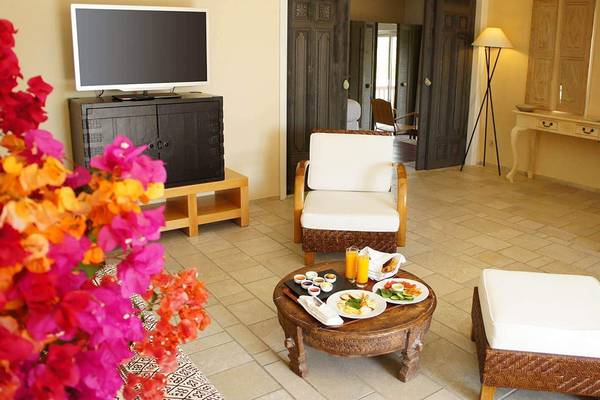Innenansicht eines Hotelzimmers im Marmara Bodrum mit Fernseher, Esstisch, Blumen und Möbeln.