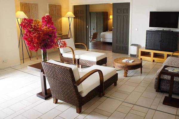 Das Wohnzimmer im Marmara Bodrum Hotel mit Fernseher, Sofa, Tisch, Blumen und Betten.