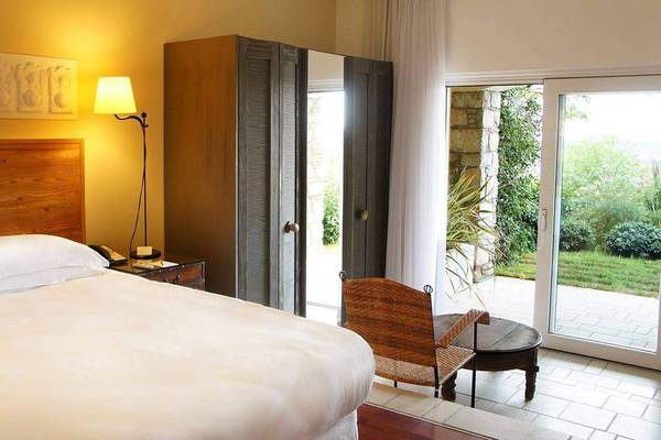 Schlafzimmer im Marmara Bodrum mit Bett, Nachttisch und offener Tür zum Garten.