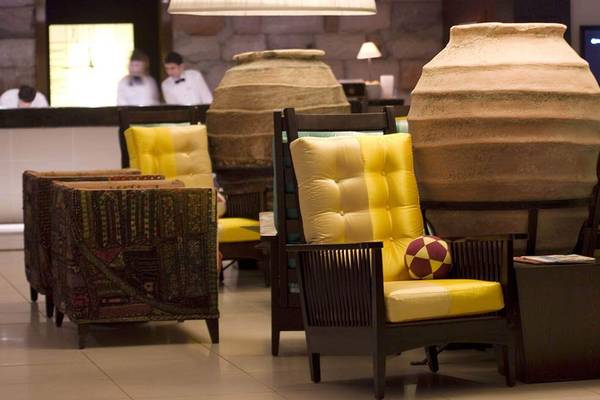 Lobby des Marmara Bodrum Hotels mit gelben Sesseln, großen Vasen und Angestellten im Hintergrund.