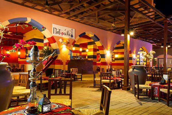 Innenansicht des Restaurants im Jaz Samaya Resort mit bunten Wänden, Tischen und Stühlen, sowie einem Wasserpfeifenbereich.