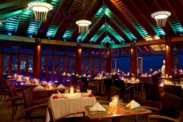 Innenansicht des Restaurants im Kuredu Island Resort & Spa mit stimmungsvoller Beleuchtung und Blick auf den Ozean.