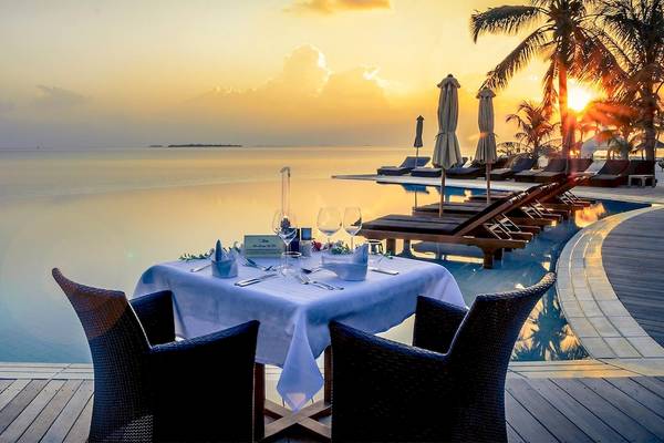 Tisch mit Tischdecken und Gläsern f ür ein Abendessen am Pool des Kuredu Island Resorts & Spa