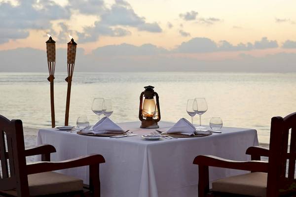 Tisch auf dem Strand des Kuredu Island Resorts & Spa bei Sonnenuntergang