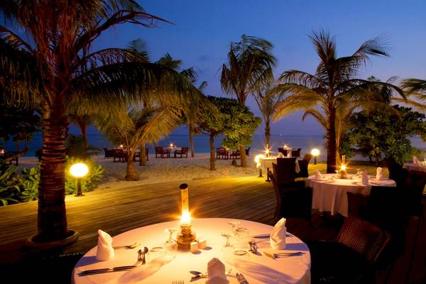 Außenbereich des Kuredu Island Resorts & Spa mit gedeckten Tischen bei Nacht.
