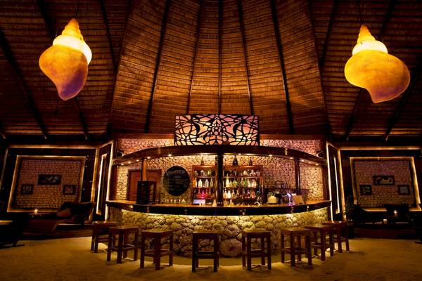 Die Bar im Kuredu Island Resort & Spa mit Steintheke und Holzstühlen.