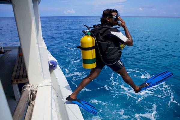 Taucher bei Kuredu Island Resort & Spa springt vom Boot ins Wasser