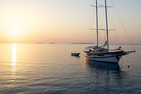 Sonnenuntergang mit einem Segelboot und einem kleinen Boot im Meer