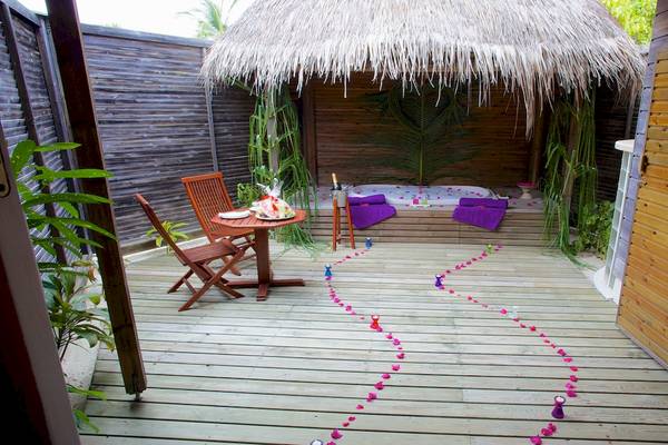 Hütte im Kuredu Island Resort & Spa mit Whirlpool und Tisch im Freien.