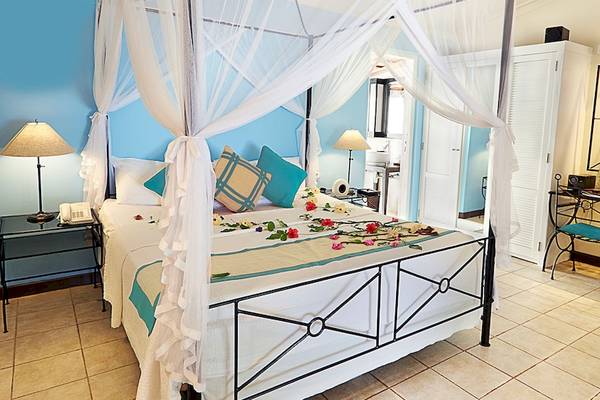 Doppelbettzimmer im Kuredu Island Resort & Spa mit Himmelbett, Blumendekoration und Schreibtisch.