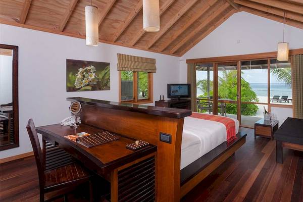 Innenansicht der Suite im Kuredu Island Resort & Spa mit Bett, Schreibtisch und Blick auf das Meer.