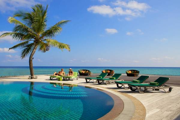 Poolbereich des Kuredu Island Resorts mit Lounge-Stühlen und Palme