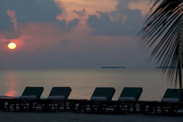 Sonnenuntergang am Strand des Kuredu Island Resort & Spa mit Lounge-Stühlen und Meer im Hintergrund