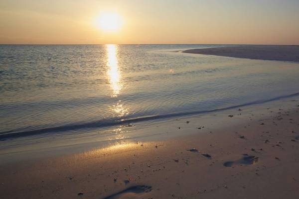 Sonnenuntergang am Strand des Kuredu Island Resort & Spa mit ruhigem Wasser und ruhigen Wellen.