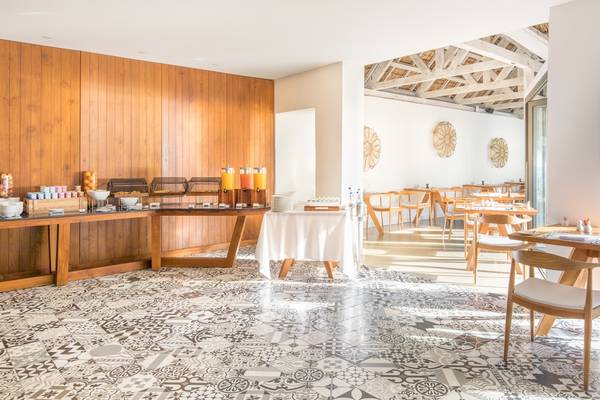 Frühstücksbereich des Seasense Boutique Hotel & Spa mit gemustertem Boden und Holzmöbeln.