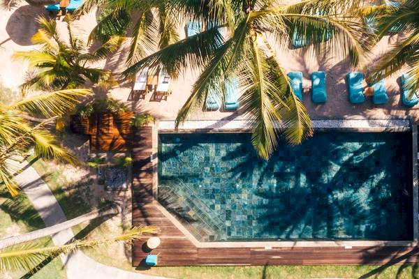 Pool des Seasense Boutique Hotel & Spa aus der Vogelperspektive, umgeben von blauen Liegen und Palmen.