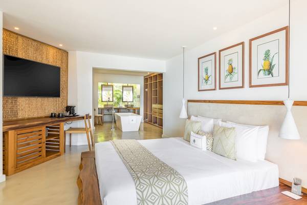 Innenansicht eines Schlafzimmers im Seasense Boutique Hotel mit großem Bett, Fernseher und Deko.