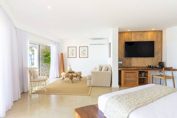 Innenansicht eines Zimmers im Seasense Boutique Hotel mit Wohnzimmer und Schlafzimmerbereich.