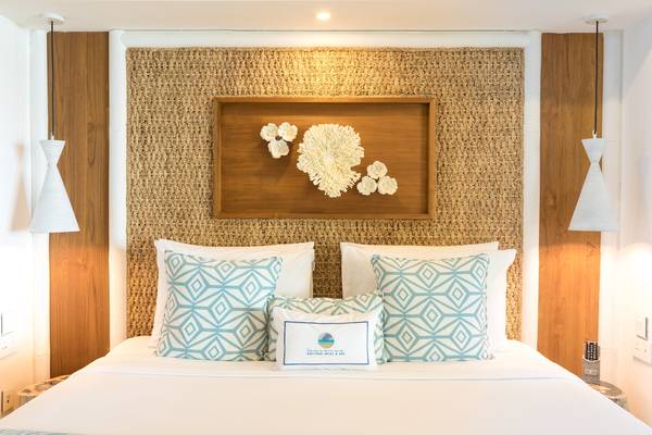 Bett im Seasense Boutique Hotel & Spa mit blauen Kissen und dekorativem Wandschmuck.