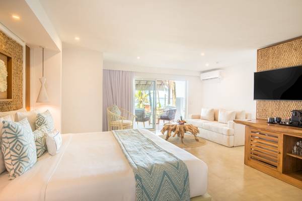 Innenansicht des Schlafzimmers im Seasense Boutique Hotel & Spa mit einem großen Bett, einer Couch und einem Fernseher.